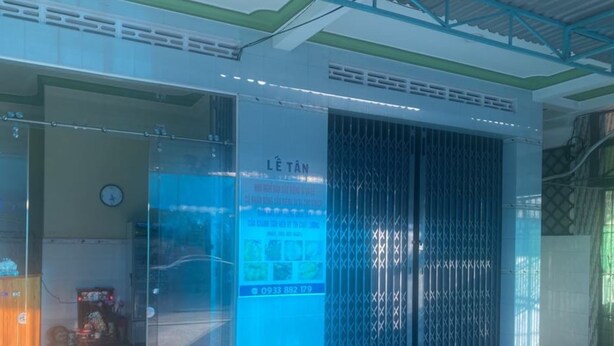 Ein modernes Gebäude mit großem Glasanbau, einer blauen Infotafel und einem Metall-Sicherheitsgitter.