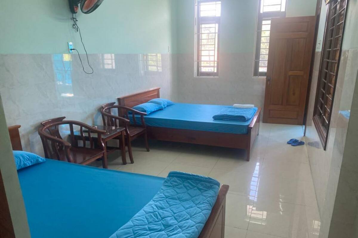 A room with two beds, a wooden chair, and a table.