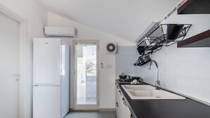 Una cocina moderna con un refrigerador blanco, una encimera negra y un lavaplatos empotrado.