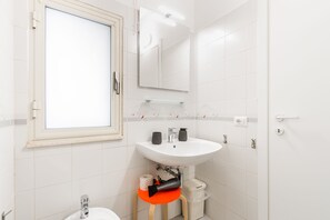 A bathroom with a white sink, mirror, and window. - Artemide Vista Mare (Ragusa)