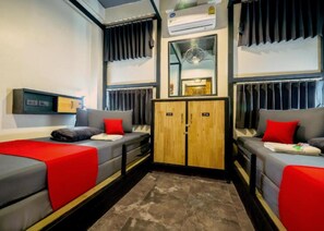 Una habitación de hotel compacta con dos camas individuales, un armario, un espejo y un aire acondicionado.