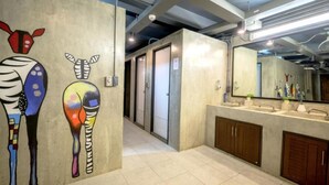 A bathroom with a tiled floor, a sink with a mirror, and a door leading to another room. - Episode 11 Hostel Sukhumvit (Bangkok)