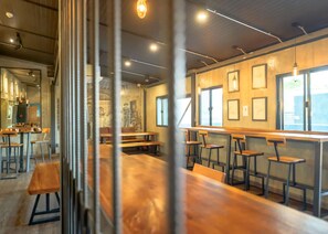 Un restaurante moderno con mesas y bancos de madera, ventanas amplias y obras de arte en las paredes.