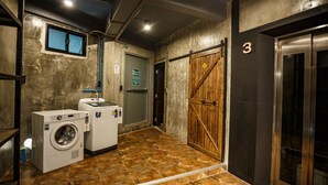 A laundry room with two washing machines, a wooden door, and an elevator. - Episode 11 Hostel Sukhumvit (Bangkok)