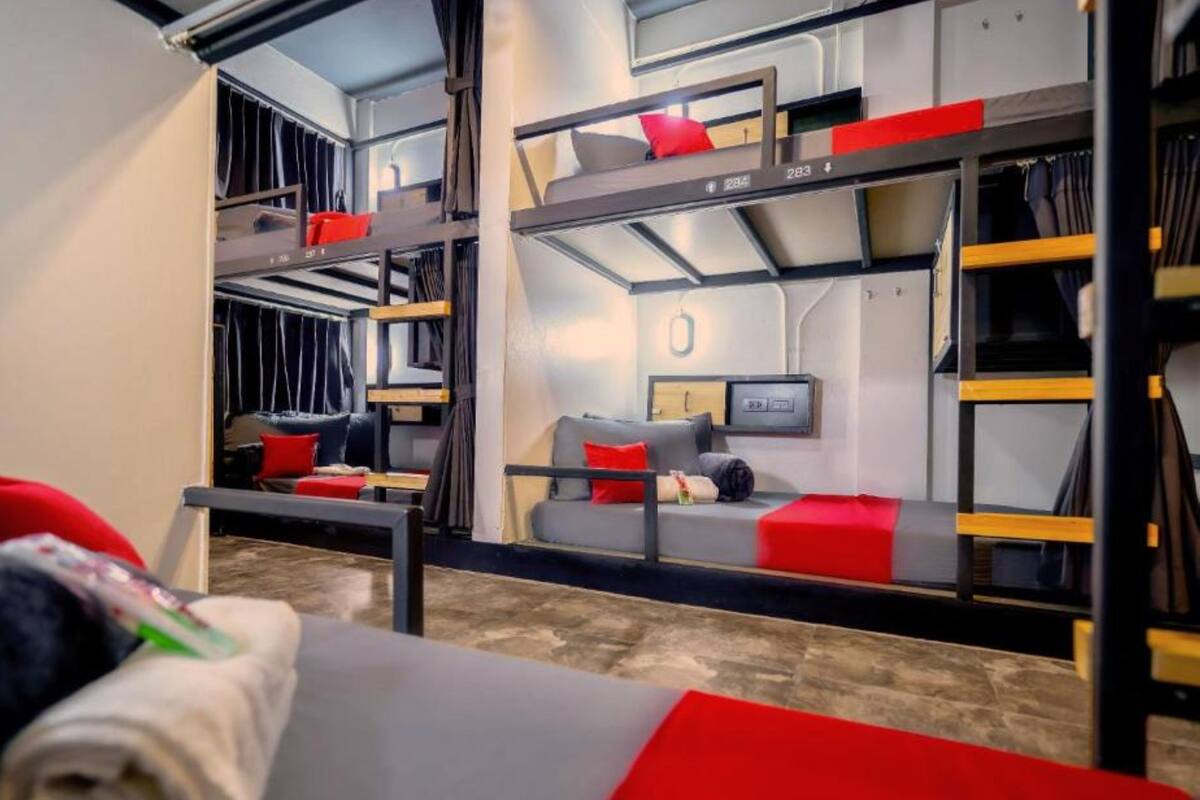 Un dormitorio con literas, un sofá, un televisor y un escritorio.