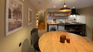 Una cocina moderna con una mesa de comedor de madera, horno empotrado y una lámpara colgante.