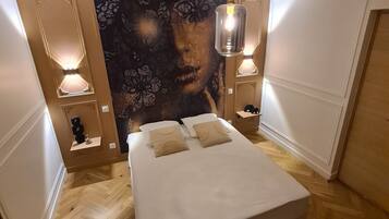 Een moderne slaapkamer met een groot bed, houten vloeren en een decoratief wandtapijt.