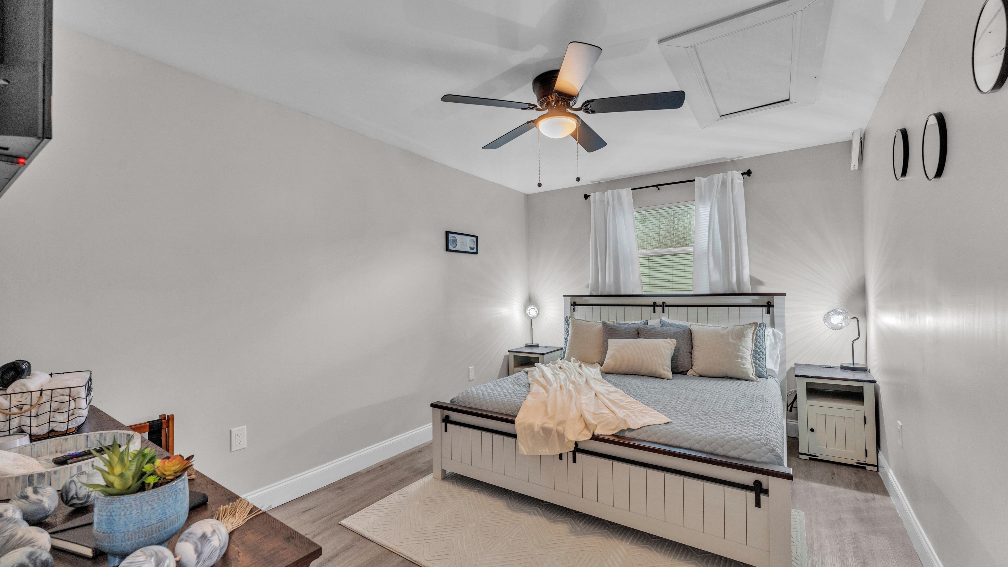 A bedroom with a bed, bedside tables, a ceiling fan, and a window with curtains.