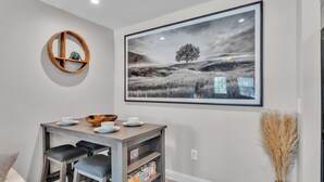 A dining area with a wooden table, chairs, and a framed landscape painting. - Modern Comfort, Pet Friendly, 2 King Beds (Winter Haven)