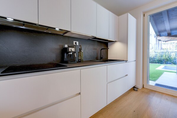 A modern kitchen with white cabinets, a black countertop, and a built-in stove.