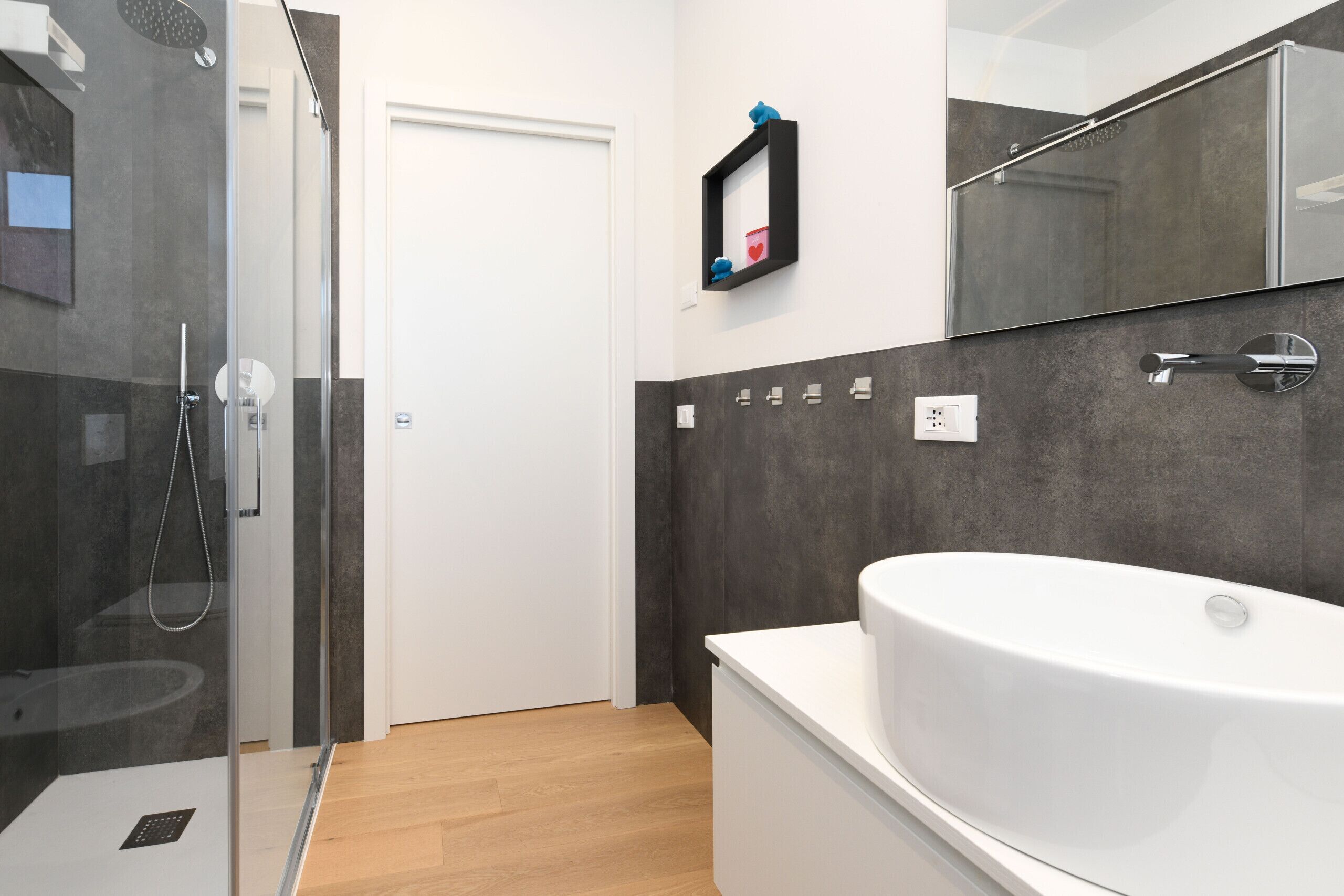 A modern bathroom with a glass-enclosed shower, a white bathtub, and a large mirror.