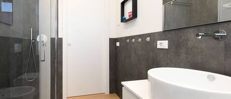 A modern bathroom with a glass-enclosed shower, a white bathtub, and a large mirror.