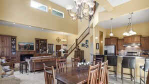 A spacious living area with a fireplace, a dining table with chairs, a kitchen with modern appliances, and a staircase leading to an upper floor. - Spacious Retreat | Incredible Views & Outdoor Space | Close to Town (Ouray)