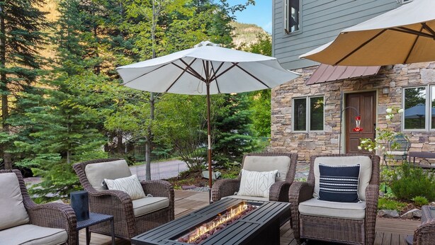 A patio with wicker furniture, a fire pit, and two umbrellas. - Spacious Retreat | Incredible Views & Outdoor Space | Close to Town (Ouray)