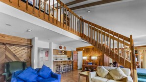 A spacious living area with a wooden staircase, a blue sofa, a white sofa, and a herringbone-patterned coffee table. - Cm425 Copper Mtn Inn 5 Bedroom Condo by RedAwning (Copper Mountain)