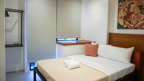 Ein Hotelzimmer mit Bett, Nachttisch, Wandregal und Gemälde.