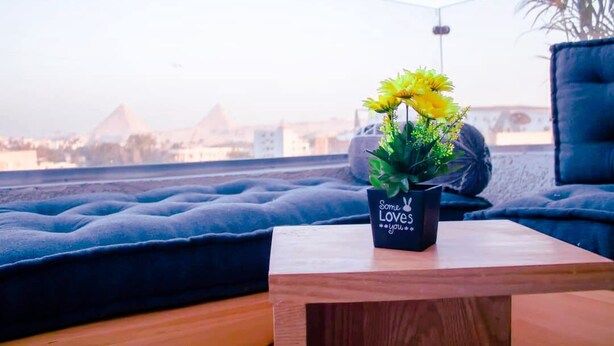 A cozy seating area with a view of pyramids, a small table with a plant, and a cushion. - king pyramid hotel (Giza)
