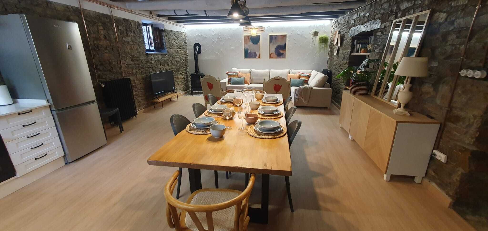 A modern kitchen with a dining area, stone walls, and a wooden dining table set for four.
