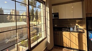 A modern kitchen with a large window, a hanging light fixture, and a view of the street outside. - Antica Jabalal-lwebdeh 5 (Amman)