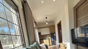 A living room with a sofa, TV, and kitchen in the background. - Antica Jabalal-lwebdeh 5 (Amman)