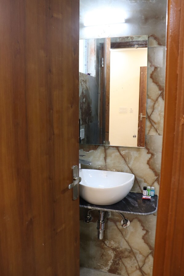 Une salle de bain avec un lavabo blanc, un miroir et un mur en marbre.