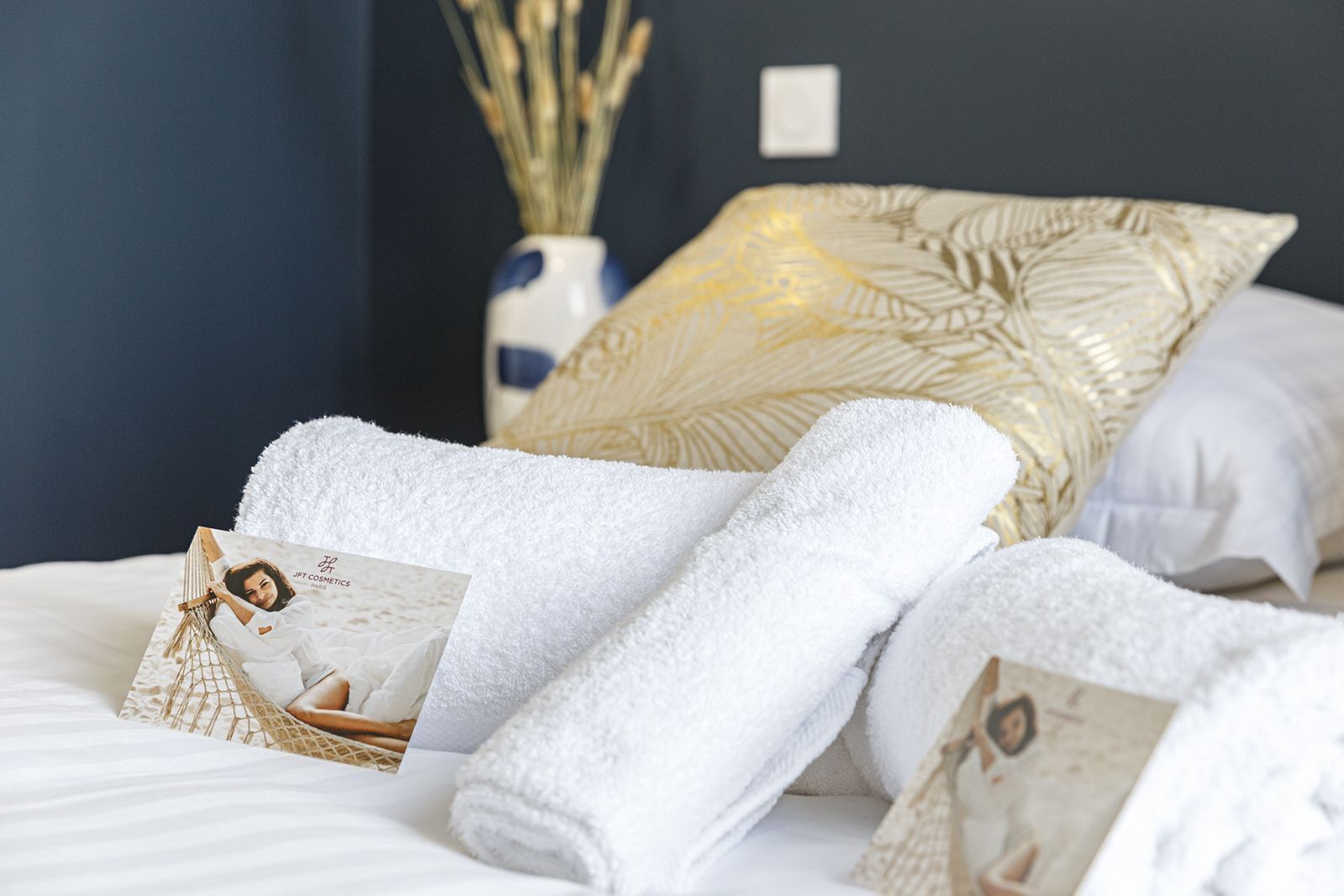 A neatly made bed with white towels and a magazine.