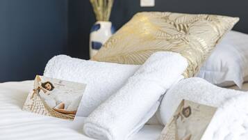 A neatly made bed with white towels and a magazine.