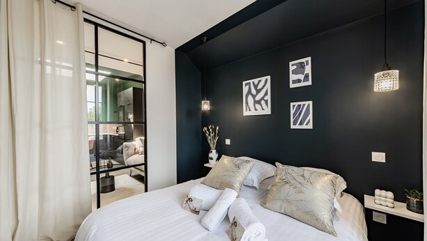 A modern bedroom with a large bed, a dark accent wall, and three framed abstract art pieces. - L'azur, Cocooning, Reposant, Déposez vos Valises et Appréciez (Segré-en-Anjou Bleu)
