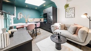A modern kitchen with a central island, a dining area with pink chairs, and a living area with a sofa and a coffee table. - L'azur, Cocooning, Reposant, Déposez vos Valises et Appréciez (Segré-en-Anjou Bleu)