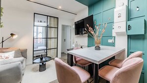 A modern living room with a sofa, a coffee table, and a dining area with pink chairs and a white table. - L'azur, Cocooning, Reposant, Déposez vos Valises et Appréciez (Segré-en-Anjou Bleu)
