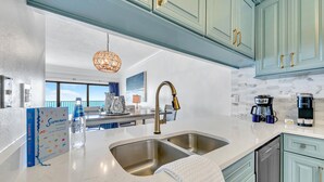 A modern kitchen with a double sink, stainless steel faucet, and a coffee maker. - 🌴Emerald Towers 1302 - Salty Smile | Private Beach Access, Panoramic Gulf Views (Destin)