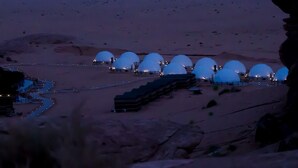 A desert landscape with multiple dome-shaped structures, likely accommodations, arranged in a semi-circle with pathways connecting them. - Desert Season Camp (Wadi Rum)