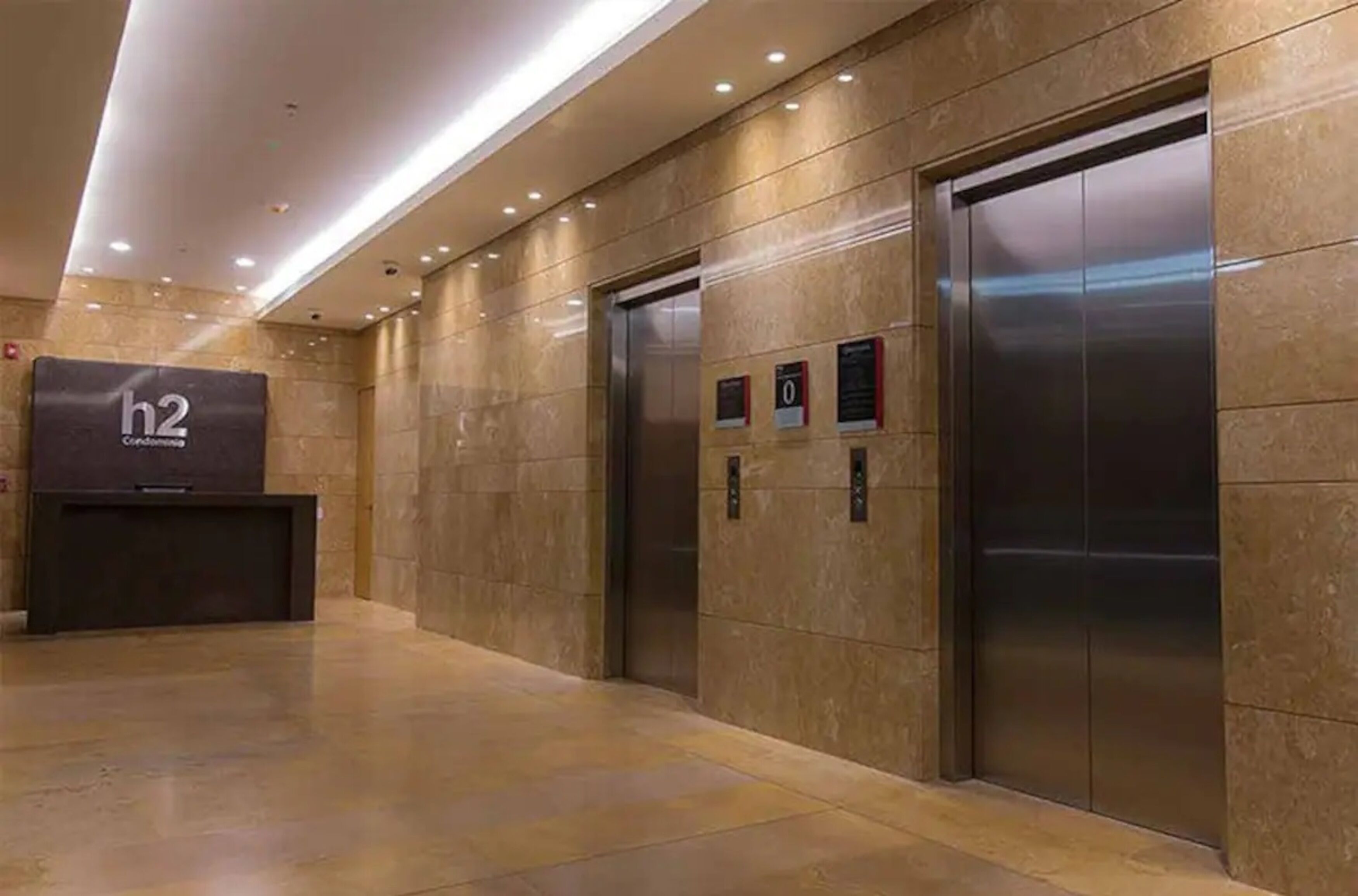 A modern elevator area with two elevators and a reception desk labeled 'h2'.