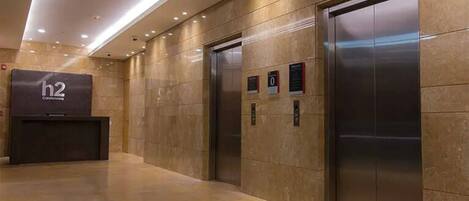 A modern elevator area with two elevators and a reception desk labeled 'h2'.