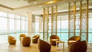 A modern lounge with wicker furniture, large windows, and a view of the sea. - Apartamento Lujoso H2 - Bocagrande (Cartagena)