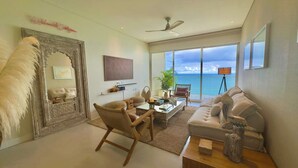 A spacious living room with a large window offering a view of the ocean, a ceiling fan, and a decorative mirror. - Apartamento Lujoso H2 - Bocagrande (Cartagena)