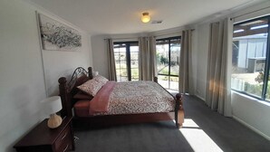 Une chambre à coucher avec un lit, une table de chevet, une lampe et une fenêtre avec des rideaux.