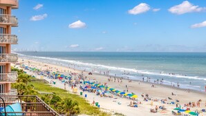 A beach with a view of the ocean and a building with balconies. - Oceanfront King Suite - Fabulous Views - King Bed - Indoor and Outdoor pools (Myrtle Beach)