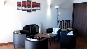 Un salon avec une cheminée, deux fauteuils, une petite table et un lampadaire.