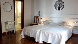 Une chambre à coucher avec un grand lit, une table de chevet, une chaise, une petite table et un miroir fixé au mur.