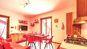 A compact living space with a dining area, kitchenette, and a TV mounted on the wall. - Happy Guest Apartments Mountain Panorama Borno (BORNO)