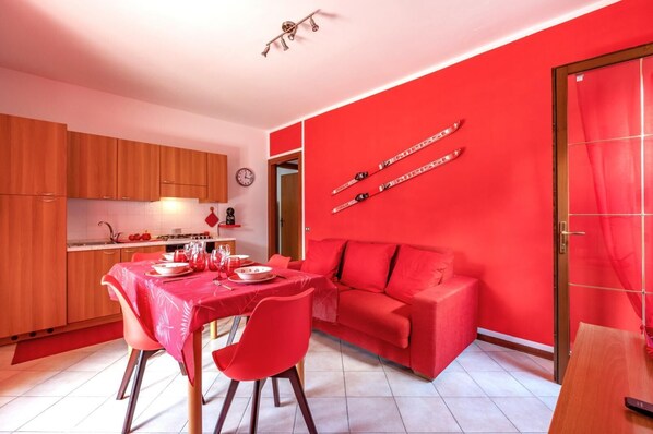 A compact living space with a dining area, kitchen, and a red sofa.