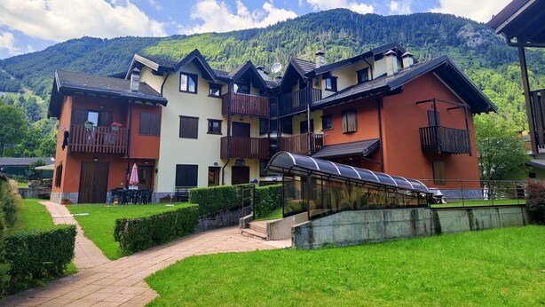 Un immeuble à plusieurs étages doté de balcons, d’une galerie couverte et ayant une chaîne de montagnes en toile de fond.