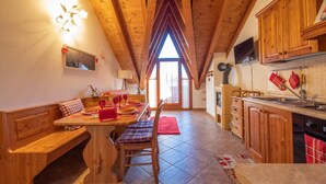 A cozy chalet-style room with a wooden dining table, benches, and a red rug.