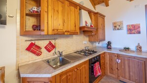 A kitchen with wooden cabinets, a gas stove, a sink, and a tiled backsplash.