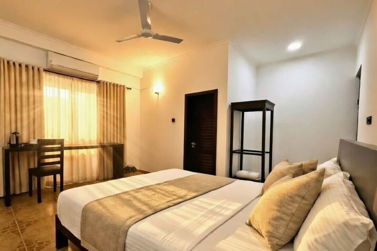 A hotel room with a bed, a desk, and a chair.