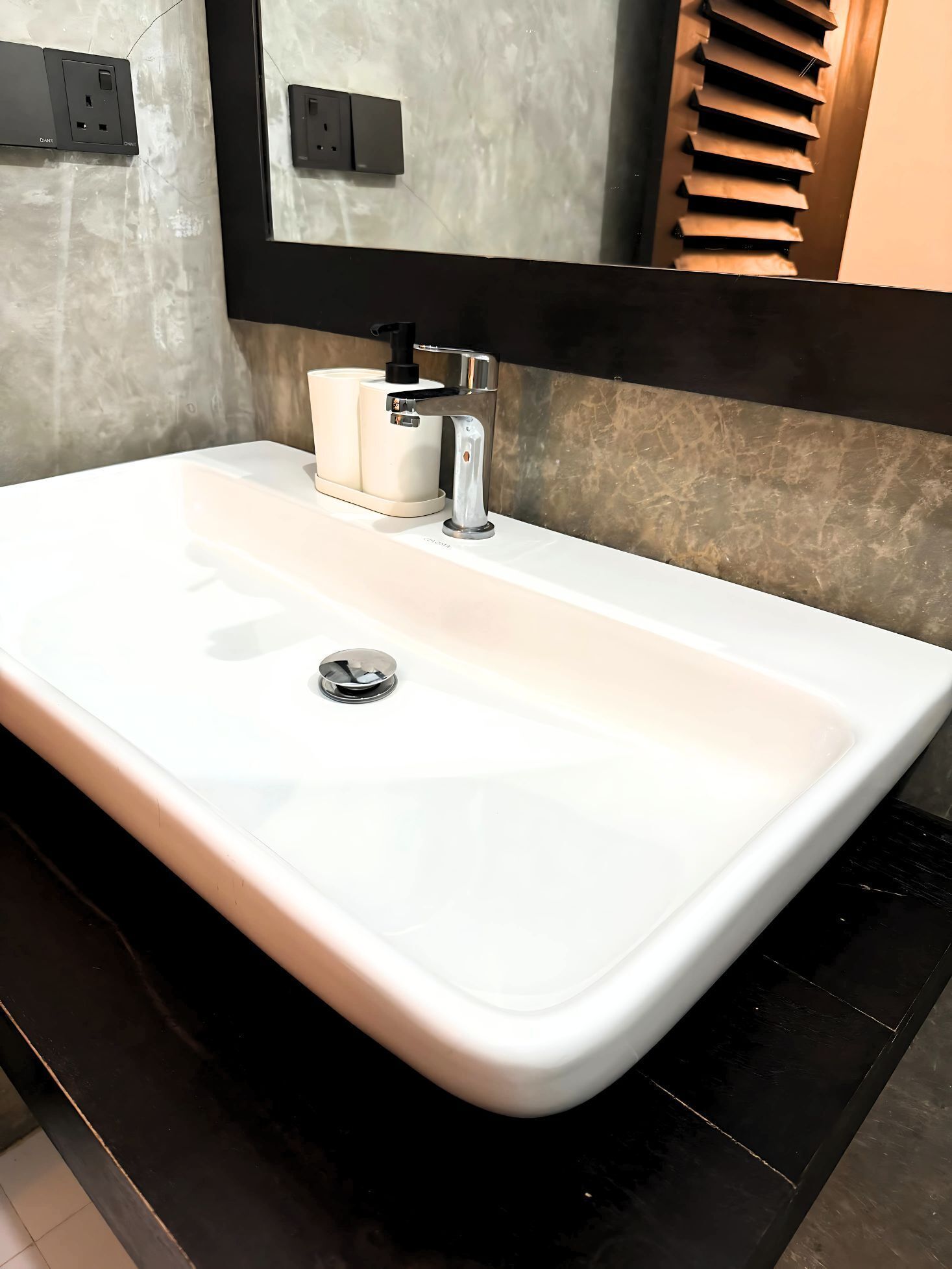 Une salle de bain moderne avec un lavabo blanc, un robinet chromé et un miroir au-dessus.
