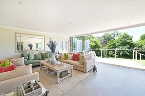 A spacious living room with a large window, a sofa set, a coffee table, and a decorative vase. - THISTLE HOUSE, FERNWOOD ESTATE , NEWLANDS CAPE TOWN (Cape Town)
