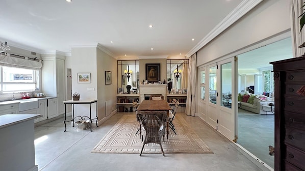 A spacious kitchen with a dining area, large windows, and a view of the living room. - THISTLE HOUSE, FERNWOOD ESTATE , NEWLANDS CAPE TOWN (Cape Town)