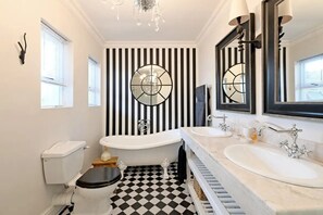 A bathroom with a black and white checkered floor, two sinks, a bathtub, and a large mirror with a circular design. - THISTLE HOUSE, FERNWOOD ESTATE , NEWLANDS CAPE TOWN (Cape Town)